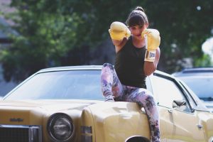 women with boxing gloves sitting on top of the car