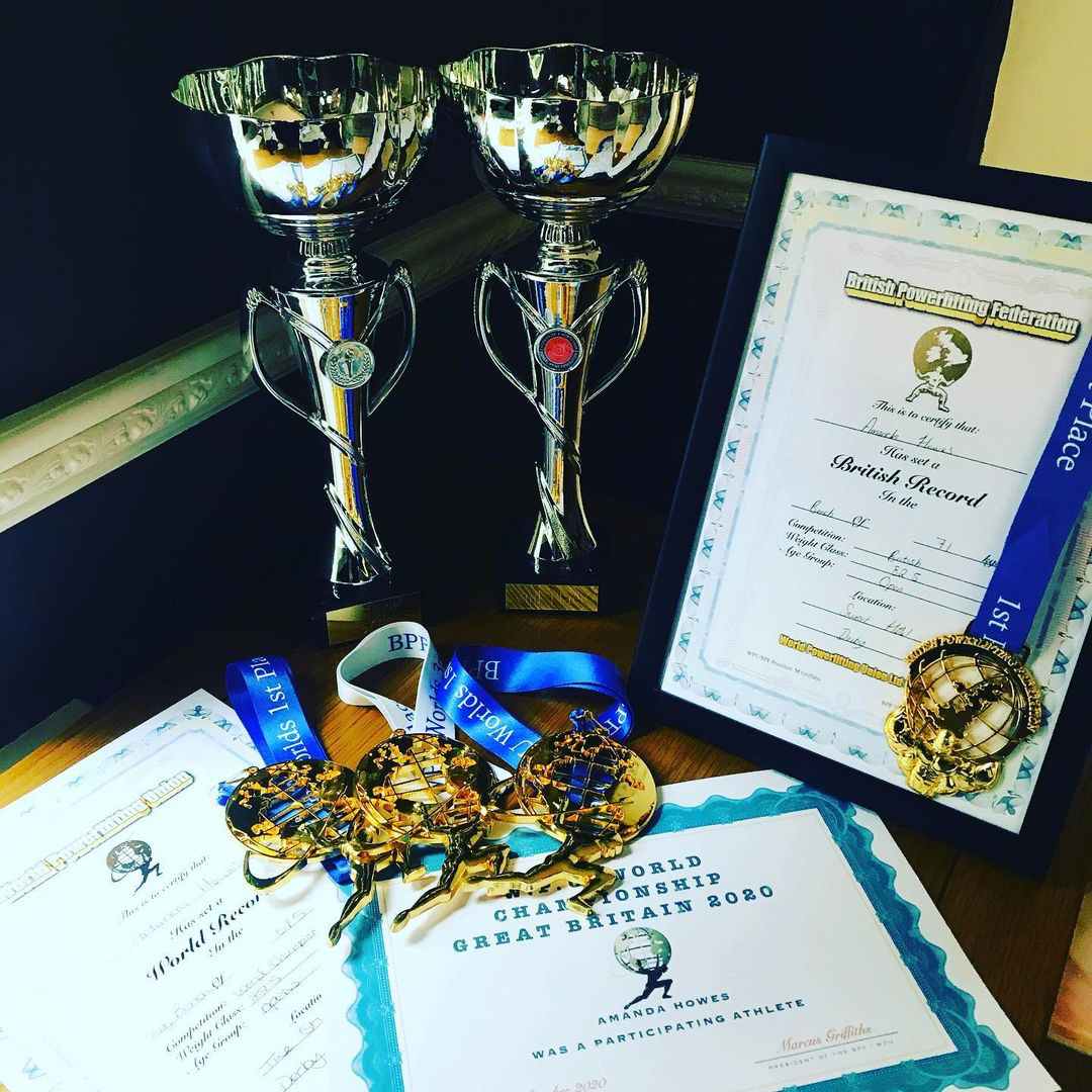 Image shows trophies, certificates and medals for powerlifting including a world record and british world record