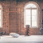 A luxury home gym design containing a ladder, an exercise bike, a rowing machine, a cable machine, a weight bench, a balance trainer, and a weight rack.