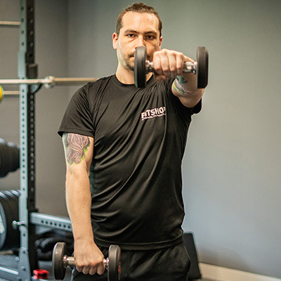 Model performing a front raise with a dumbbell. the model's left arm is raised. 