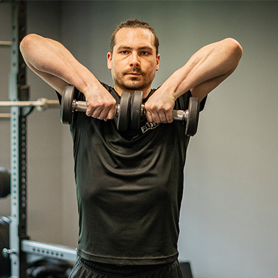 model performing an upright row with dumbbells.