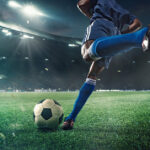 A footballer about to kick a soccer ball in a stadium.
