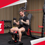 A person lifting dumbbells in a home gym setup.